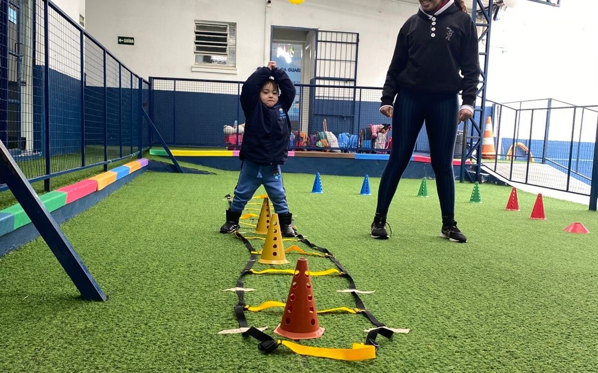 Professora acompanhando criança no circuito psicomotor